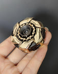 Gold and black fidget spinner held in a hand against a dark background