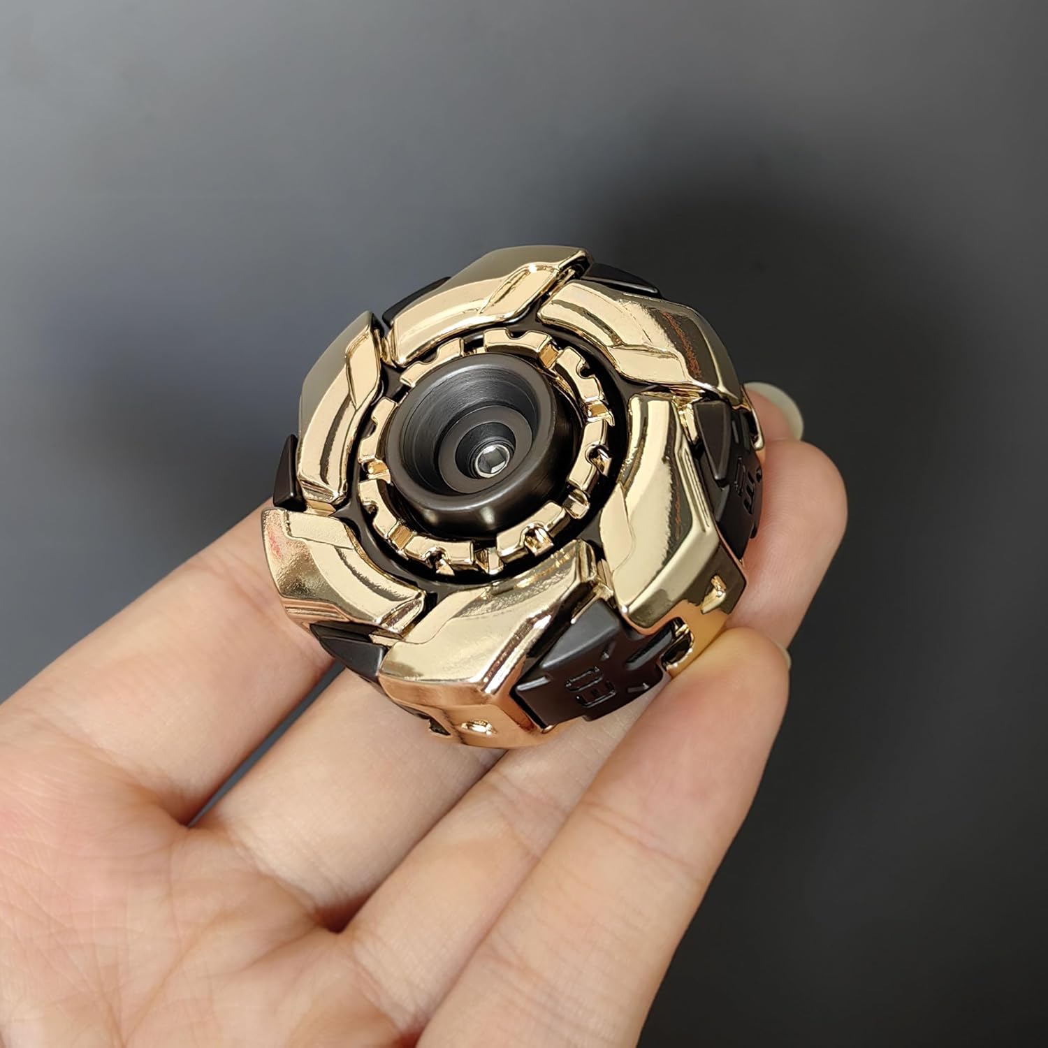Gold and black fidget spinner held in a hand against a dark background
