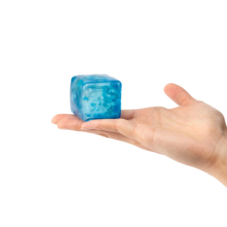 Blue ice cube held in a hand on a white background