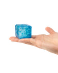 Blue ice cube held in a hand on a white background